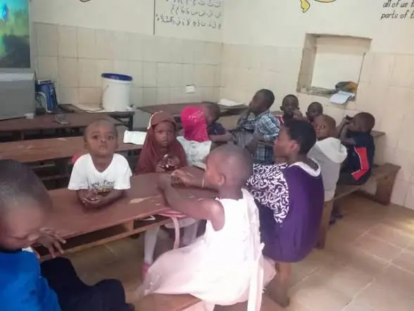 Children and adults seated around tables during an indoor activity