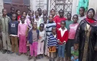 Children and adults posing together outside a building